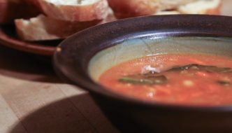 Bowl of soup with bread in the background